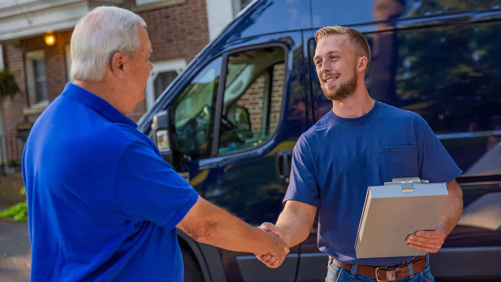 HVAC technician shaking the hand of a homeowner in front driveway