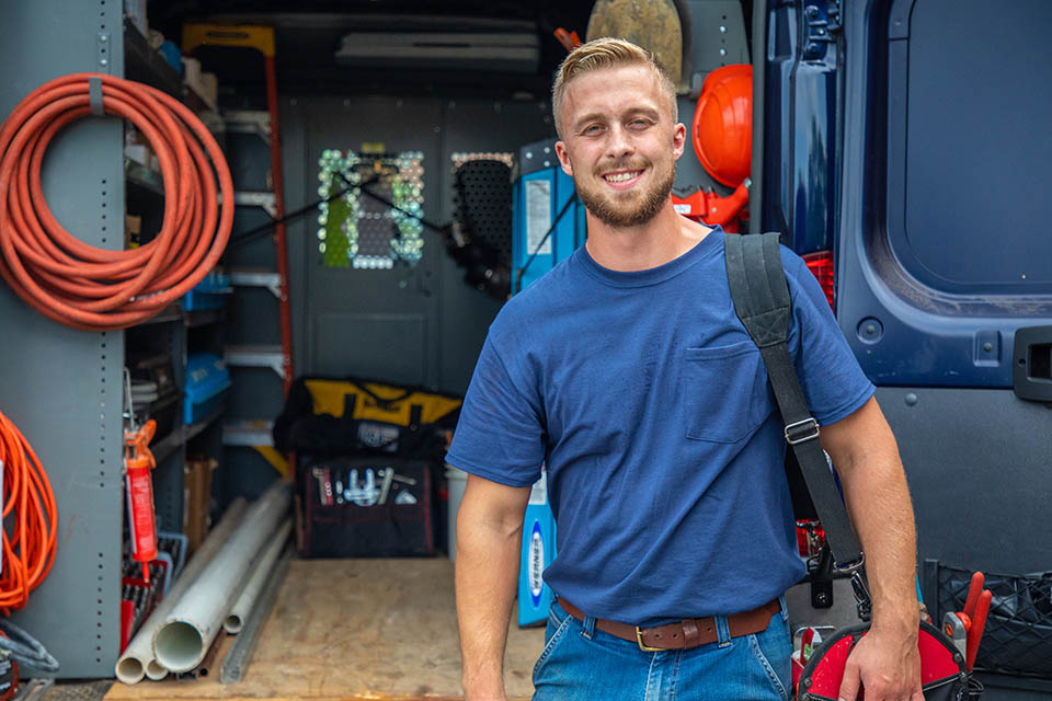 Generator technician smiling in front of his service van